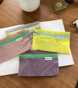 Vierteiliges Set aus Nylon-Organizern in Pastellfarben auf einer Holzoberfläche