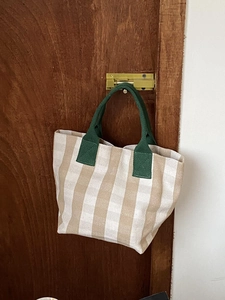 Minimalist beige and white striped canvas tote bag with contrast dark green handles