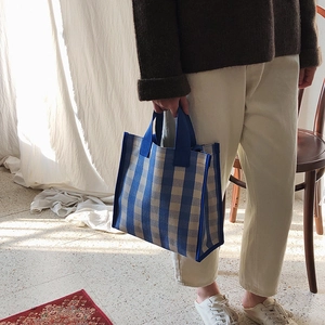 Close-up of blue and white striped tote bag with sturdy woven texture and handle details