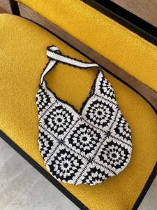 Handmade crochet tote bag with black and white floral pattern on a yellow chair