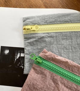 Nahaufnahme von Nylon-Netztaschen mit Kontrast-Reißverschluss auf Holzschreibtisch