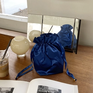 Luxurious navy blue satin drawstring storage bag with golden beads on a wooden desk