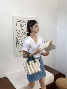 Minimalist checkered canvas tote bag with green handles styled with casual summer outfit