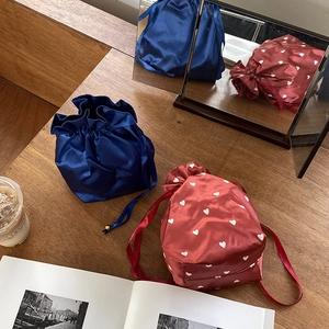Close-up of satin drawstring storage bags with heart pattern on a wooden desk