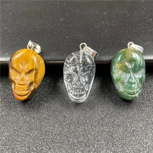 Three natural crystal skull pendants in tiger eye, quartz, and aventurine stones