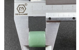 Macro shot measuring a 13.5mm cylindrical green jade bead with a digital caliper