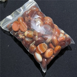 Detailed view of polished oval red banded agate stones in a clear packaging bag