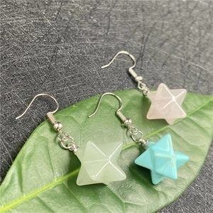 Three Merkaba star stone earrings in pink, green, and turquoise on green leaves
