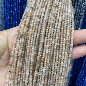 Macro detail of faceted 2-3mm natural stone beads in pale orange held by hand