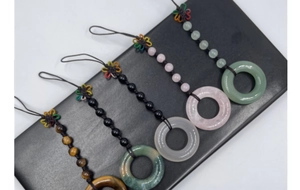 Detail showing five natural gemstone bag charms including rose quartz and tiger eye stones