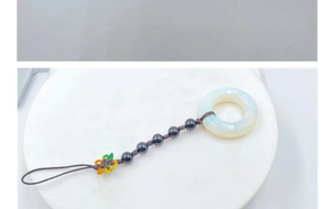 Detail of woven rainbow flower charm with black beads and a white agate ring pendant