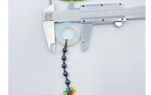 Macro shot measuring 31mm synthetic opal pendant diameter with digital calipers