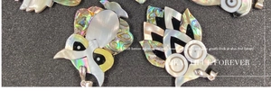 Detailed view of owl pendants crafted from natural abalone and white shells with metal loops