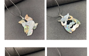 Macro shot of owl pendant with white and abalone shell inlays on black cord necklace