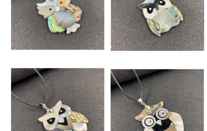 Detail of owl pendant necklaces featuring abalone shell and mother of pearl inlays