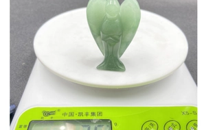 Detailansicht der handgeschnitzten grünen Edelstein-Engelfigur auf einer Waage