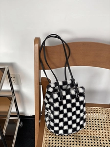 Gros plan du sac seau à damier en peluche avec texture fausse fourrure sur chaise