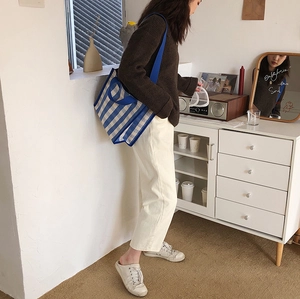 Detailed side view of blue and white checkered canvas tote bag worn by a model