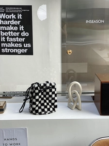 Détail d'un sac seau en peluche à damier avec bandoulière en cuir dans un décor moderne