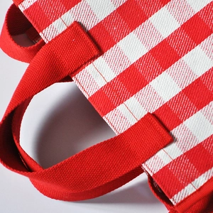 Close-up of red and white gingham tote bag with reinforced red canvas straps