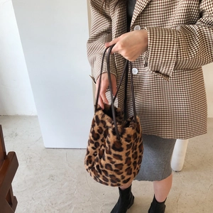 Détail du sac seau en fausse fourrure léopard avec anses en cuir porté avec une tenue