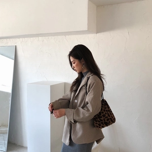 Gros plan sur un sac seau en peluche léopard assorti à un blazer à motif pied-de-poule