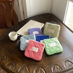 Detailed close-up of colorful corduroy mini cosmetic bags with quilted pattern on a desk