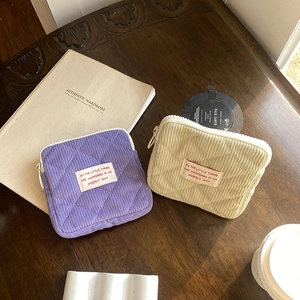 Quilted corduroy mini makeup pouches in purple and beige on a wooden table