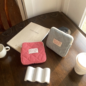Quilted corduroy mini makeup pouches in pink and blue on a vintage wooden desk