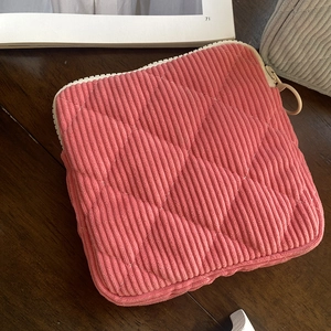 Close-up of pink corduroy mini bag with quilted rhombus pattern and ring zipper detail