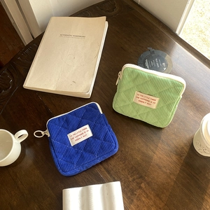 Flat lay of quilted corduroy cosmetic pouches in blue and green on a wooden table