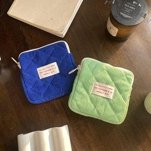 Quilted corduroy mini makeup bags in blue and green on a rustic wooden table