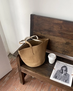 Macro view of hand-woven straw tote bag with canvas lining on a vintage wooden bench