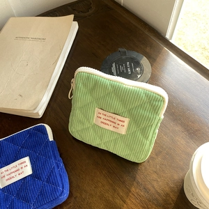 Detailed macro view of quilted corduroy mini makeup bags in green and blue colors