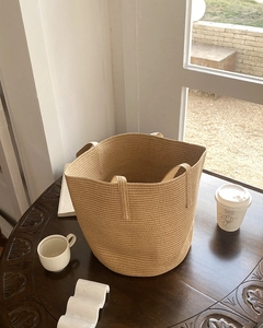 Close-up of a natural straw woven tote bag on a rustic table in a warm cafe setting