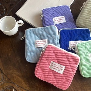 Close-up of quilted corduroy makeup bags in various colors on a wooden surface