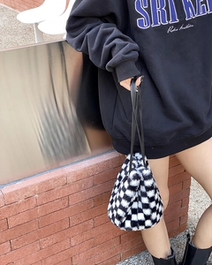 Détail du sac à bandoulière en peluche à damier noir et blanc avec sangle noire