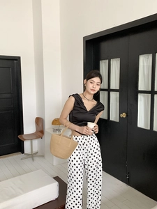 Close-up of a stylish woven straw bucket bag paired with a polka dot outfit
