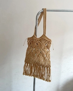 Detail of handmade macramé straw shoulder bag with long fringes and drawstring lining