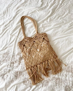 Detail of handmade macrame straw bag with geometric weave patterns and long fringes