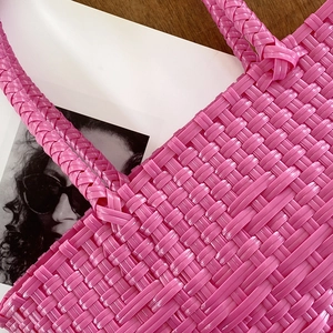 Close-up of bright pink handmade woven tote bag showing detailed texture and glossy finish