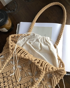 Detail of hollow crochet straw bag with a beige cotton drawstring inner lining