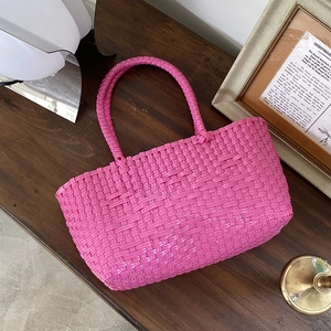 Detail of hand-woven bright pink tote bag with textured craft on vintage wooden table