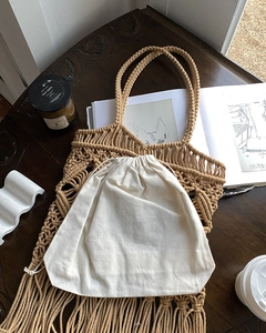 Detail shot of handmade macramé tassel bag with drawstring pouch on vintage wooden table