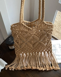Macro detail of handmade bohemian straw bag with fringe and woven hollow patterns