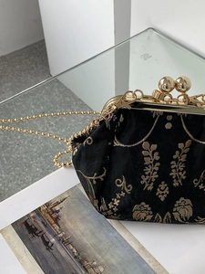 Detail of vintage black kiss lock bag with gold floral embroidery and bead buckle