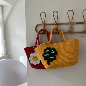 Close-up of handmade woven tote bags with flower pendants in red and yellow cotton rope