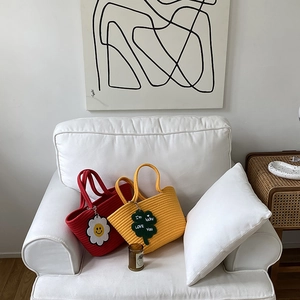 Detail of red and yellow handmade woven tote bags with flower and clover charms