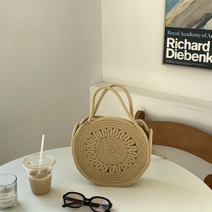 Sac à main rond en paille tressée avec motif floral sur une table de café chic