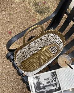 Detailed macro view of gold and white woven basket bag showing fine metallic fiber texture